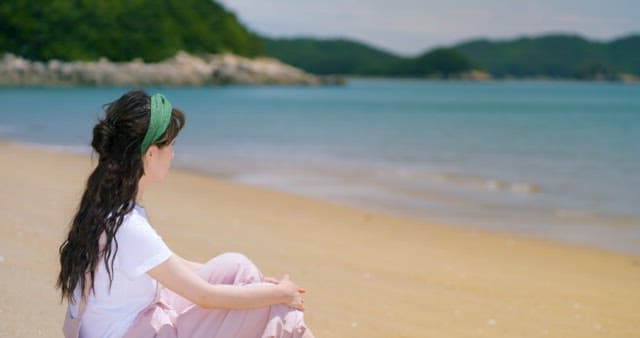 Woman Sitting Peacefully on a Sunny Beach
