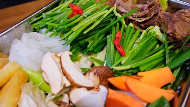 Broth for hotpot poured over fresh vegetables and meat prepared in a pot