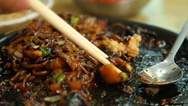 Seafood Jjajangmyeon on an iron plate with sweet and sour pork