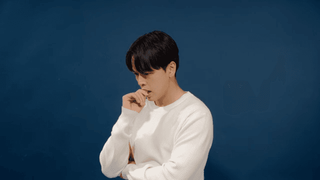 Man in a white sweater with his arms crossed and a serious expression on his face