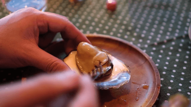 Eating oyster on a wooden plate with sauce sprinkled on it