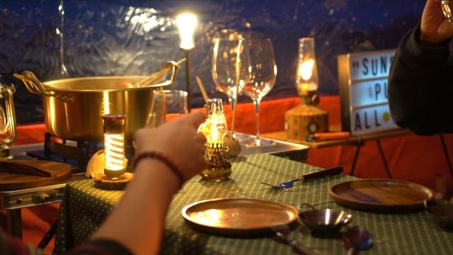People enjoying fish cake skewers and drinks in a cozy tent at night