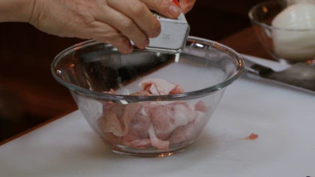 Seasoning pork with pepper in a glass bowl