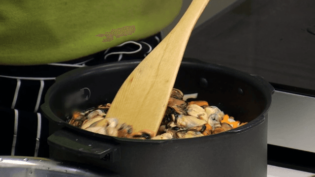 Adding chopped vegetables and fresh mussels to the rice cooker