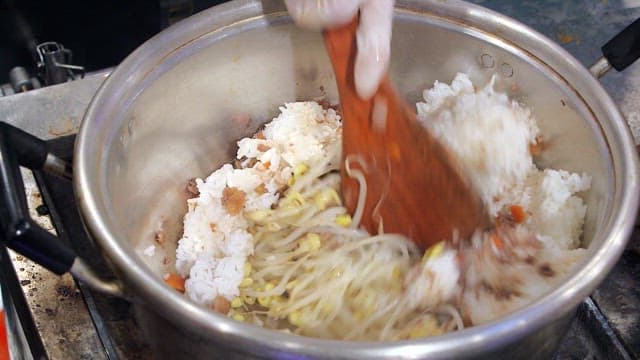 Mixing rice and bean sprouts in a pot