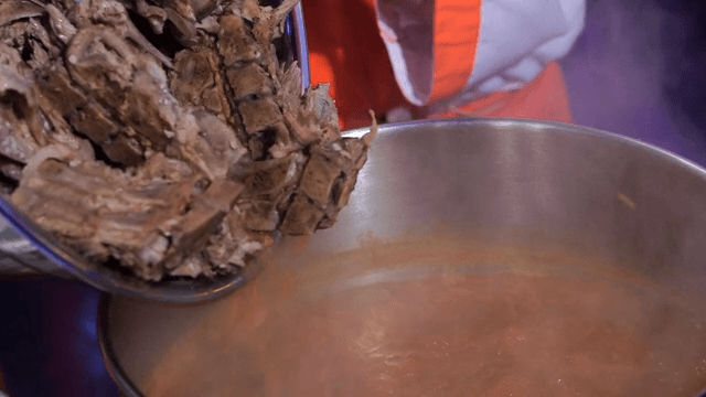 Pork backbones being added to a seasoning broth