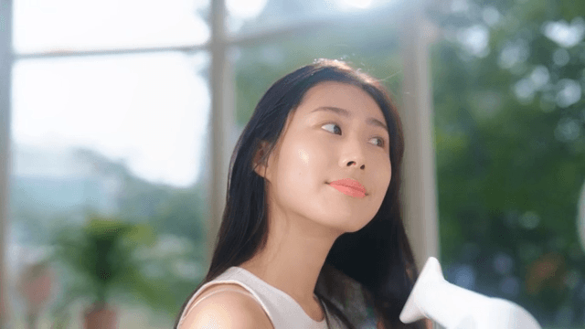 Woman drying her hair with a hair dryer in the sunshine