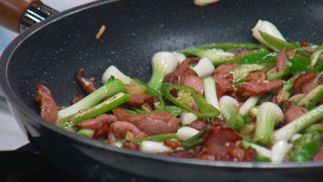 Frying pan with fresh green onions and smoked duck cooked together