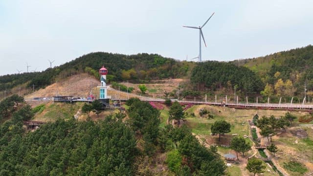 Lighthouse and wind turbines on a hill
