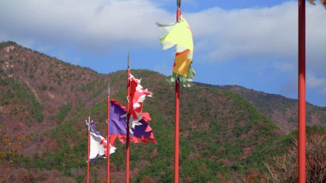 Colorful traditional flags fluttering on poles against a backdrop of green hills and blue sky