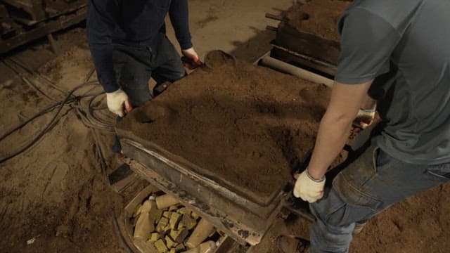 Workers handling sand molds in a factory