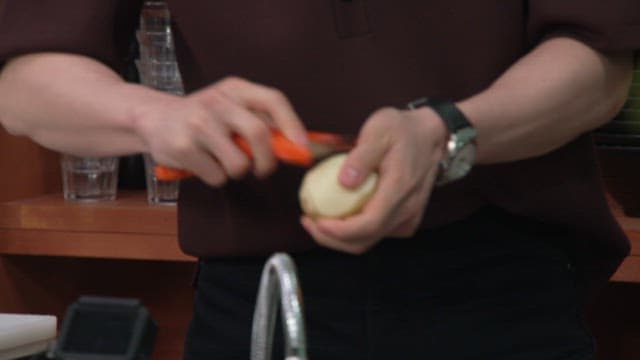 Peeling a Potato with an Orange Peeler in the Kitchen