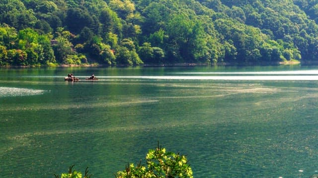 People rowing a small boat on a blue lake
