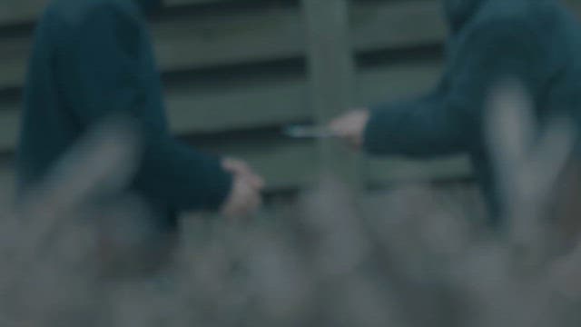 Two People Exchanging an Object Outdoors