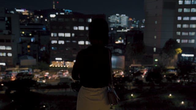 Woman Overlooking the Night View of the City at Night