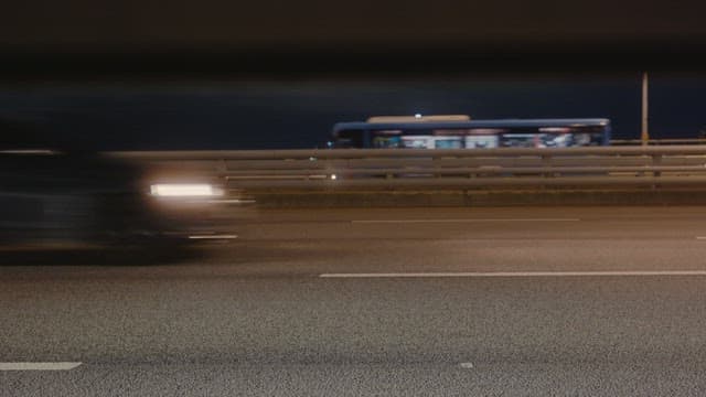 Cars and buses passing on an urban highway at night