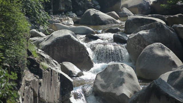 Cool water flowing through rocky valley on a sunny day