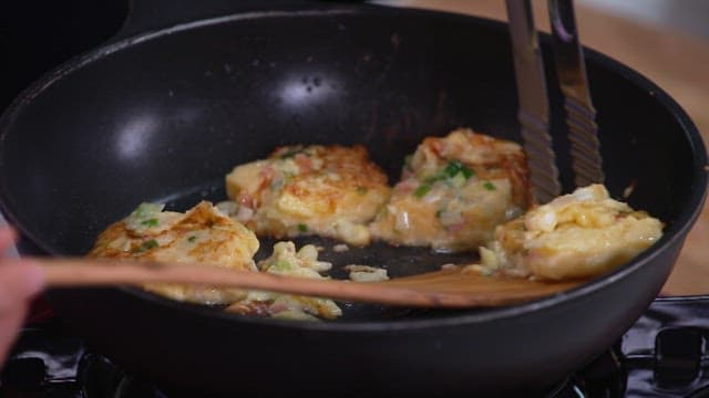 Cooking slices of bread coated with green onion and egg mixture in a frying pan