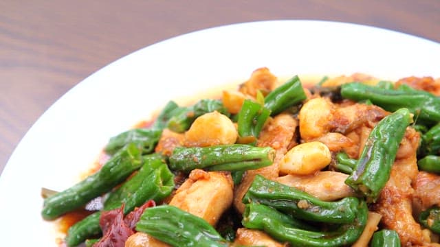 Appetizing braised spicy chicken with chili peppers on table