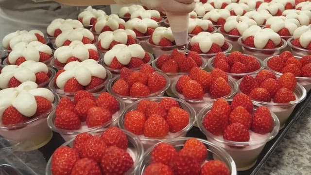 Strawberry desserts being decorated with whipped cream