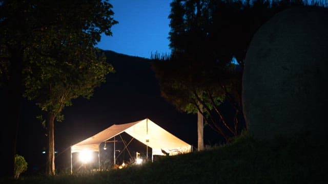 Illuminated outdoor tent in a forest at night