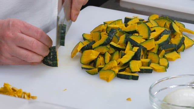 Cutting Pumpkin with a Knife on a Cutting Board in the Kitchen