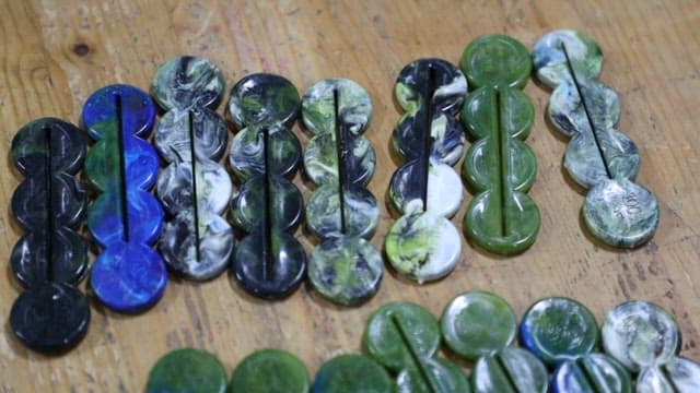 Tube squeezers of various colors made from recycled plastic on a wooden table