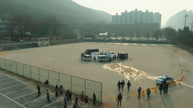 Police cars and people surrounding the crime scene in an empty lot