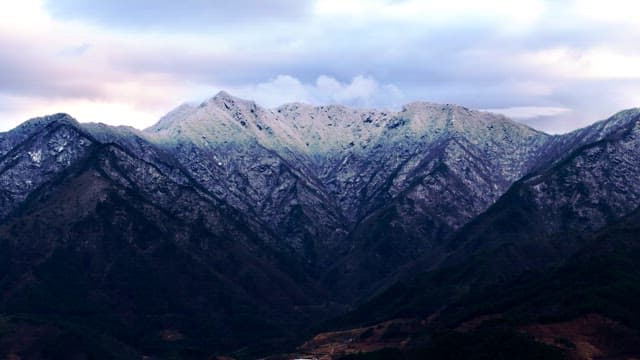 Snow-covered mountains under cloudy skies