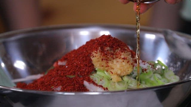 Adding fish sauce to make julienne Korean radish salad 