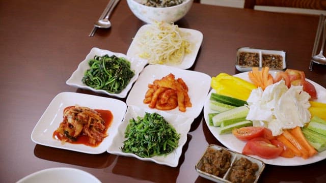 Table with vegetables, kimchi, fresh vegetables and rice
