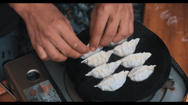 Preparing Dumplings on an Outdoor Pan