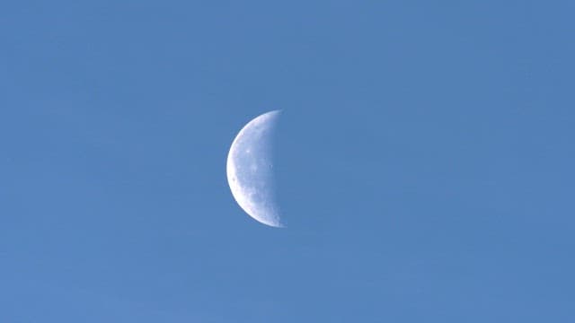 Crescent moon gradually becoming obscured during the day