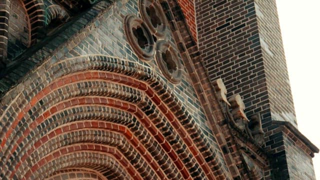 Gothic-style brick church tower with intricate arches and trefoils.