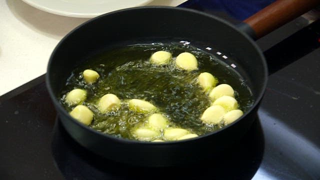 Garlic cloves frying in a pan
