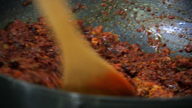 Stirring a spicy red paste in a pan
