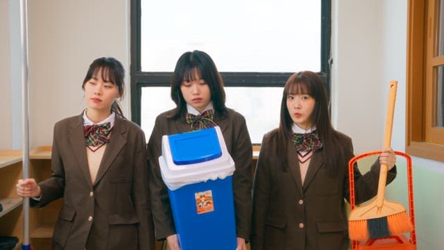 Students in school uniforms holding cleaning tools