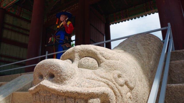 Guard wearing hanbok guarding the palace gate next to haetae statue
