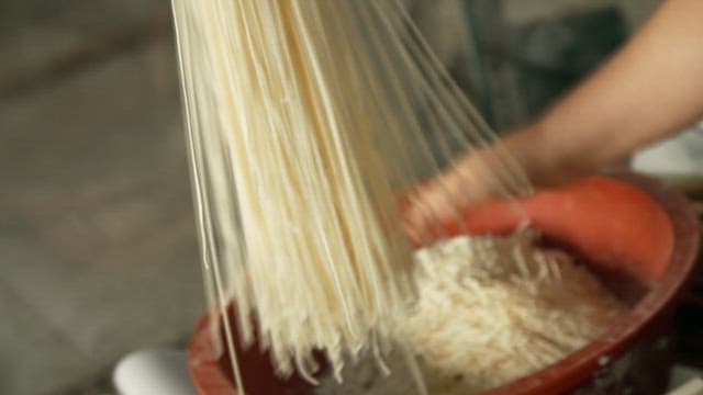 Hand preparing freshly made noodles in a traditional kitchen setting
