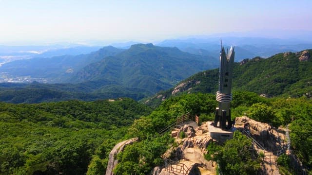 Mountain landscape with a tower commemorating the summit under a clear sky