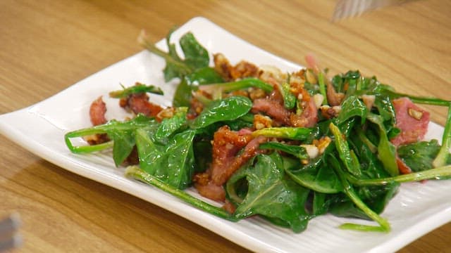 Bacon spinach stir-fry, served with tongs and a plate