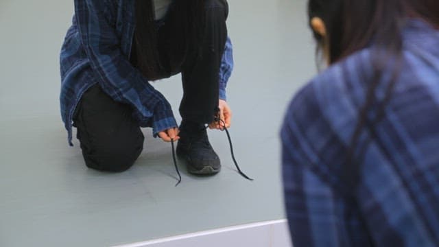 Person Tying Their Shoe Laces Indoors