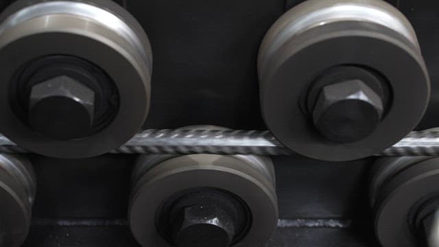 Metal rod being processed by rollers