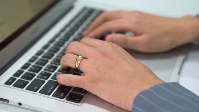 Hands typing on a laptop keyboard indoors