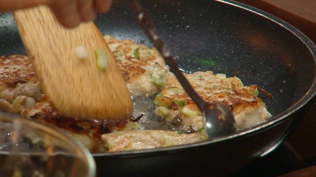 Cooking donggeurangtang in an oiled frying pan with a wooden spatula and spoon