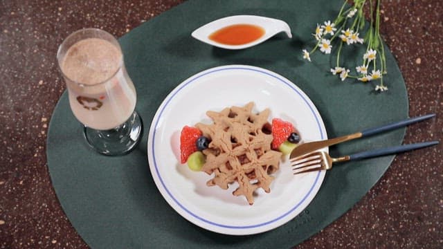 Plate of waffles topped with fresh fruit and a sweet drink
