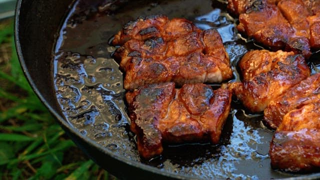 Grilling steaks on a hot frying pan, cutting with scissors