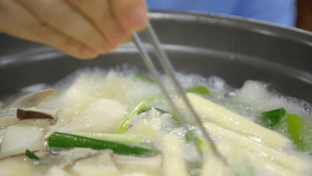 Chicken hotpot rice cake picked up with chopsticks