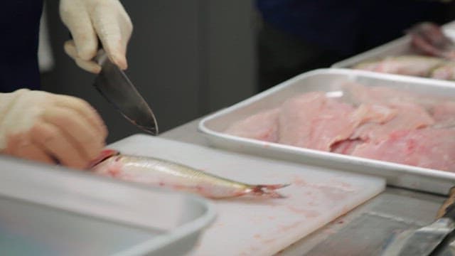 Fresh fish being slashed with a knife on a kitchen cutting board