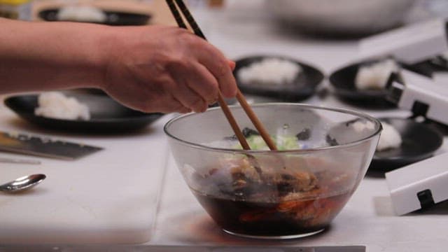 Marinated corvina being placed in a frying pan in the kitchen